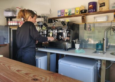 Barista preparing coffee at a professional espresso machine inside eco friendly horsebox.