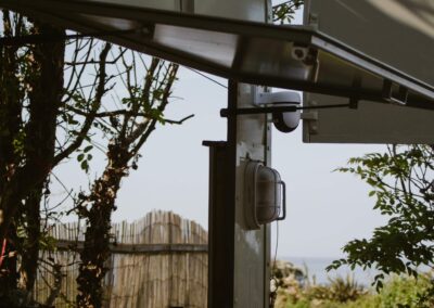 "Side view of open café trailer hatch with trees, rustic fence, and a glimpse of the sea in a peaceful natural setting."