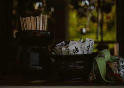 "Fairtrade sugar sachets and wooden stirrers in ceramic pots, with a floral cloth bag in an eco-friendly trailer café."