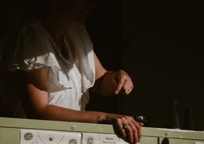 "Smiling café server leaning over the hatch of a trailer café, with the Beare Necessities menu for drinks and breakfast items visible in warm light."